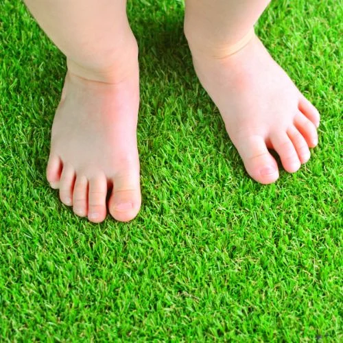 A young child bare foot on artificial grass lawn