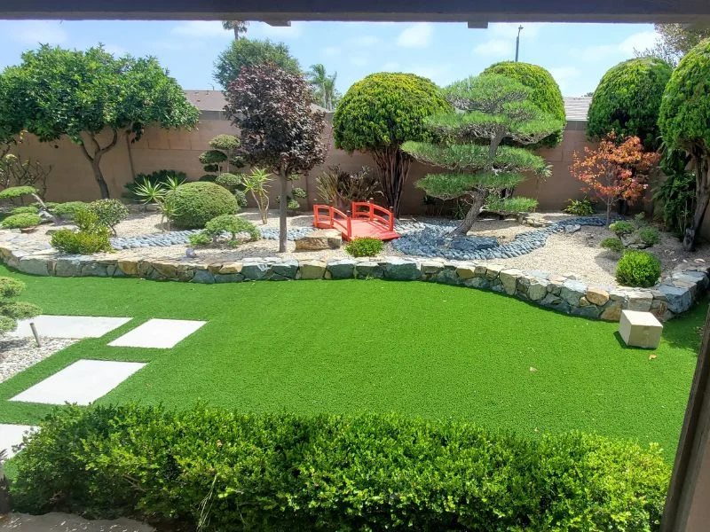 A synthetic lawn with inset concrete pavers and hardscape with a wall in Orange County, California