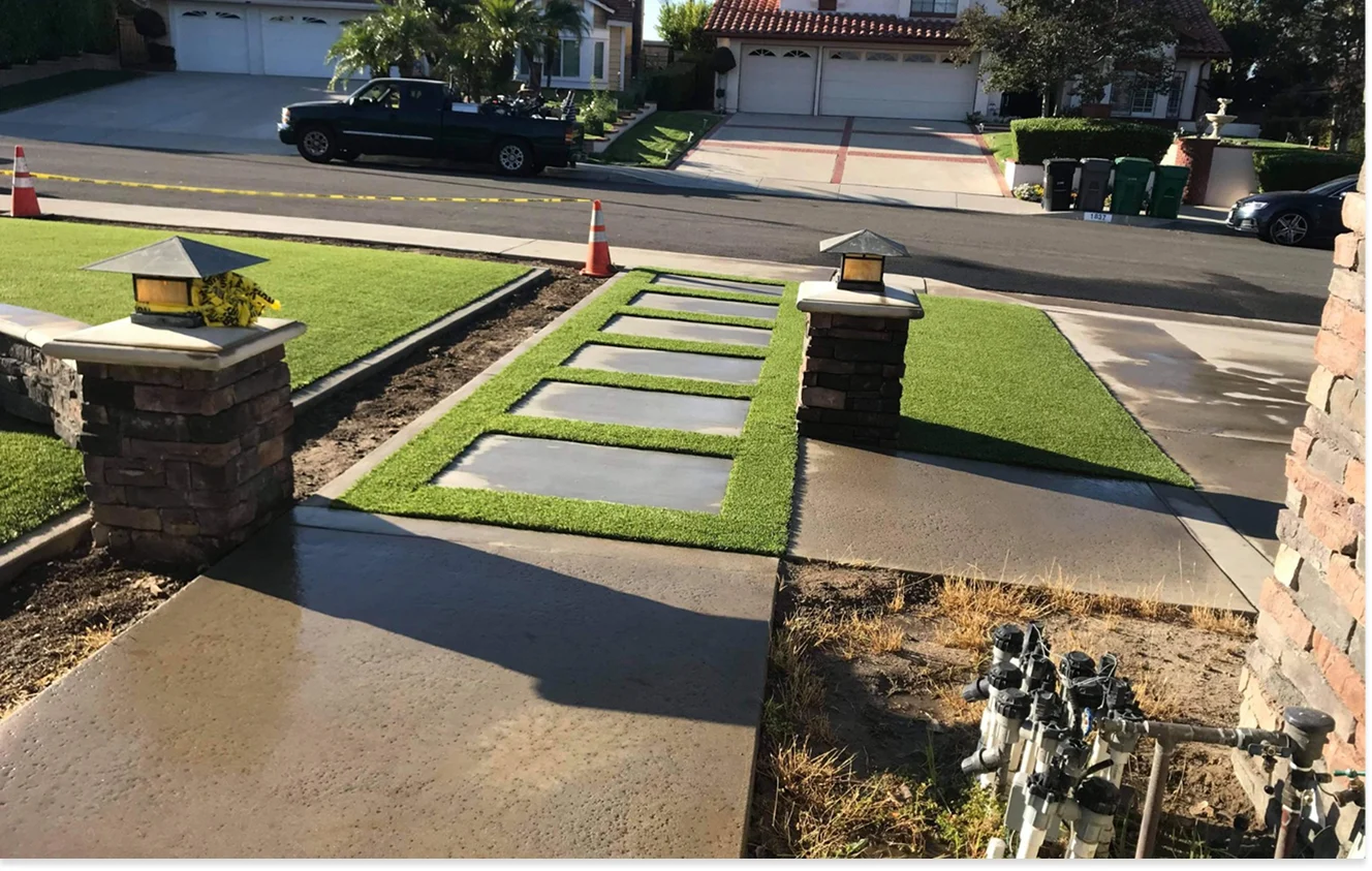 Front yard with concrete path and stepping-stone walkway across a lawn toward the street; orange traffic cones visible in the background.